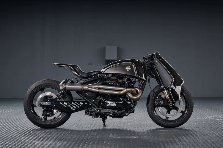 Royal Enfield Shotgun 650 x Rough Crafts, uma motocicleta customizada em preto fosco com detalhes dourados e componentes artesanais, exibida em um fundo escuro.