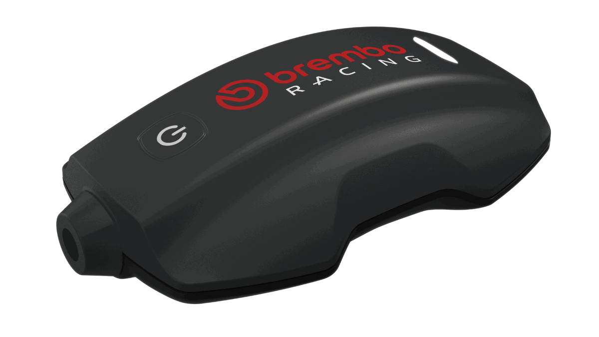 Sistema Brembo TrackTribe sendo exibido, destacando sua interface digital e o prestigioso troféu Red Dot Award, simbolizando a inovação em monitoramento de dados para motociclismo.
