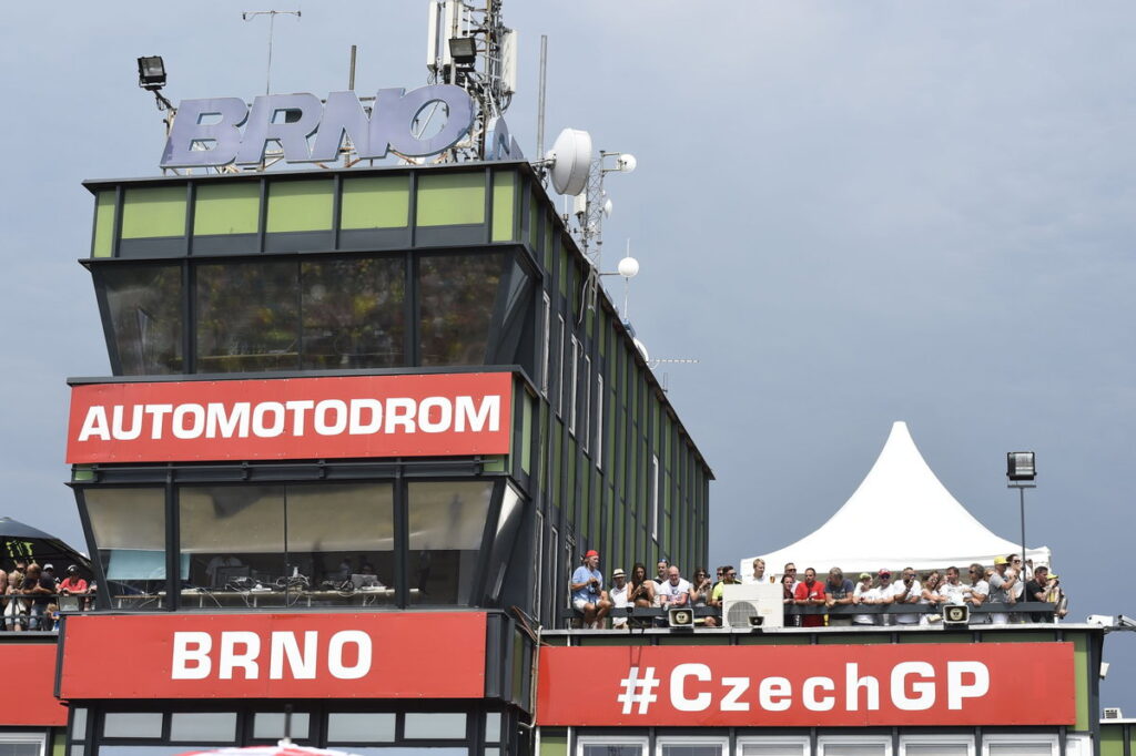 Dois pilotos de motociclismo em alta velocidade durante uma corrida FIM no circuito de Brno, República Tcheca, momentos antes de um trágico acidente que resultou em suas mortes.