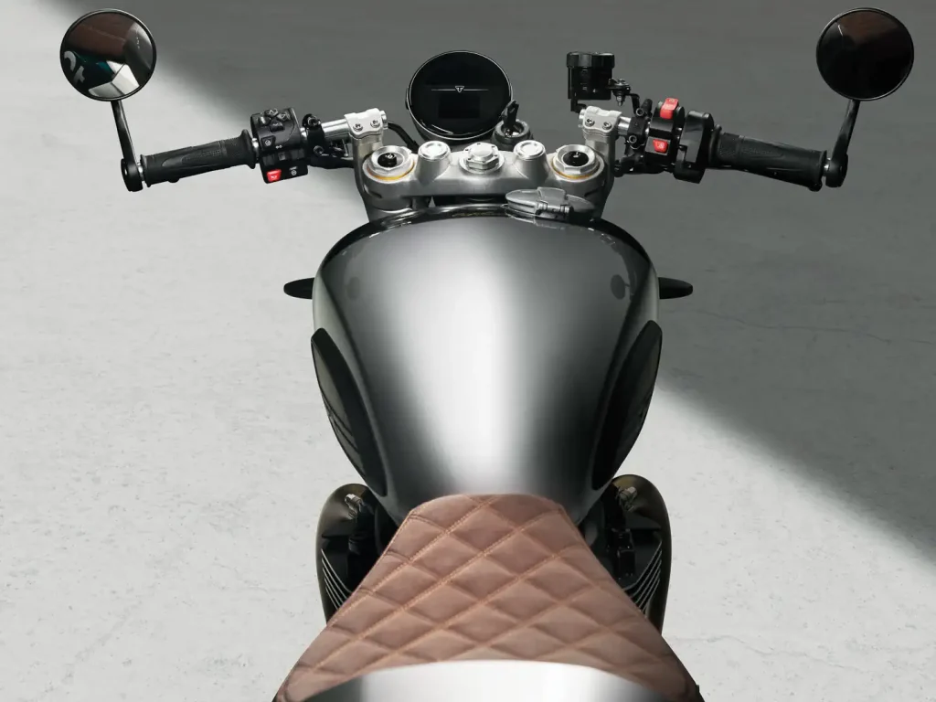 Triumph Speed Twin 1200 Cafe Racer Edition 2027, uma motocicleta clássica moderna com carenagem frontal e estilo retrô em uma estrada europeia, detalhe do farol.