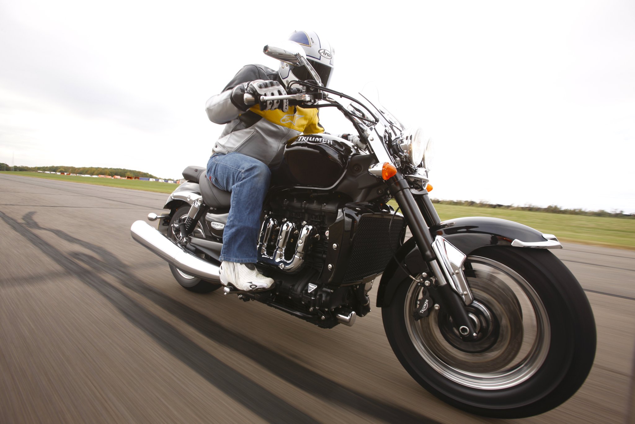 Cena humorística de engenheiros da Triumph utilizando ferramentas exageradas para montar a massiva motocicleta Rocket III, em um vídeo de marketing viral que satiriza o gigantismo do modelo.