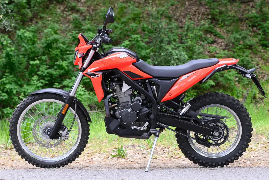 Detalhes da nova motocicleta 2026 Beta Alp 4.0 em trilha de terra com paisagem ao fundo, destacando seu design robusto e pneus de uso misto.