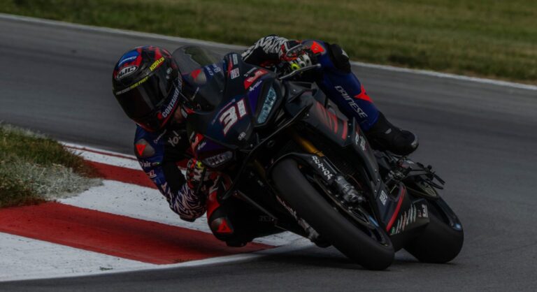 Hank Vossberg pilotando a Aprilia RS 660 em alta velocidade na pista de Mid-Ohio durante a competição da Twins Cup no MotoAmerica, em uma curva acentuada com outros competidores ao fundo.
