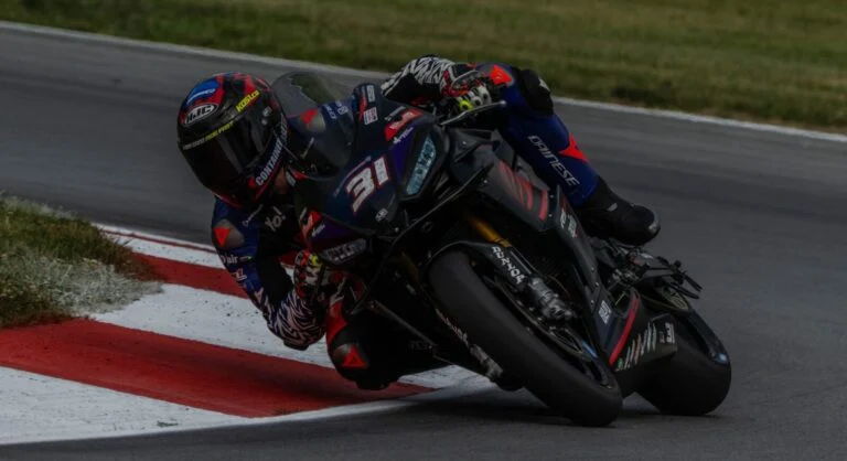 Hank Vossberg pilotando a Aprilia RS 660 em alta velocidade na pista de Mid-Ohio durante a competição da Twins Cup no MotoAmerica, em uma curva acentuada com outros competidores ao fundo.