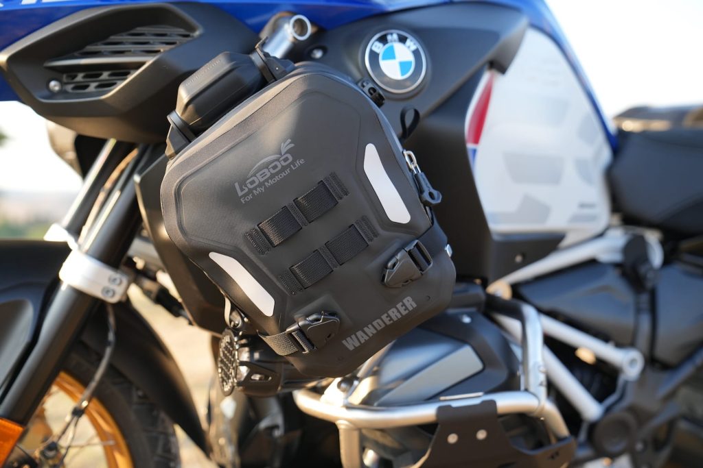 Bolsa Loboo Wanderer de cor preta fixada em uma barra de proteção de uma motocicleta de aventura, destacando sua integração com a estrutura da moto.