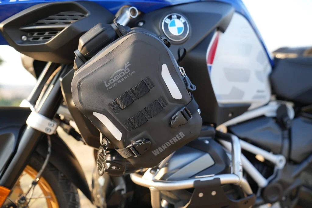 Bolsa Loboo Wanderer de cor preta fixada em uma barra de proteção de uma motocicleta de aventura, destacando sua integração com a estrutura da moto.