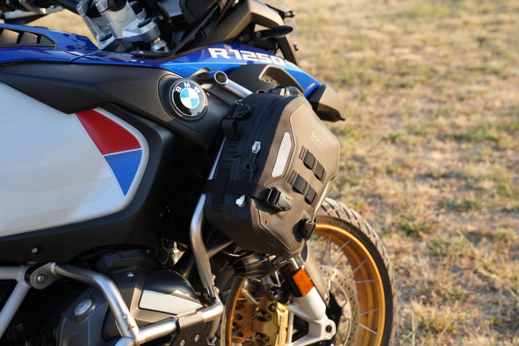 Bolsa Loboo Wanderer de cor preta fixada em uma barra de proteção de uma motocicleta de aventura, destacando sua integração com a estrutura da moto.