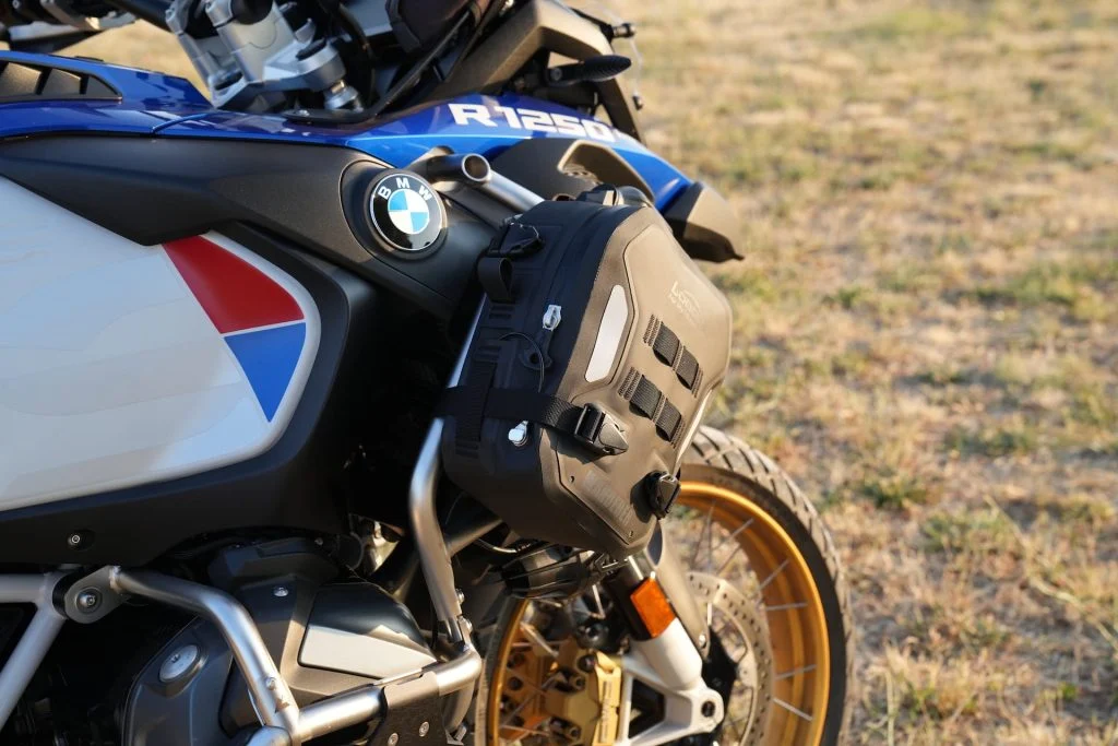 Bolsa Loboo Wanderer de cor preta fixada em uma barra de proteção de uma motocicleta de aventura, destacando sua integração com a estrutura da moto.