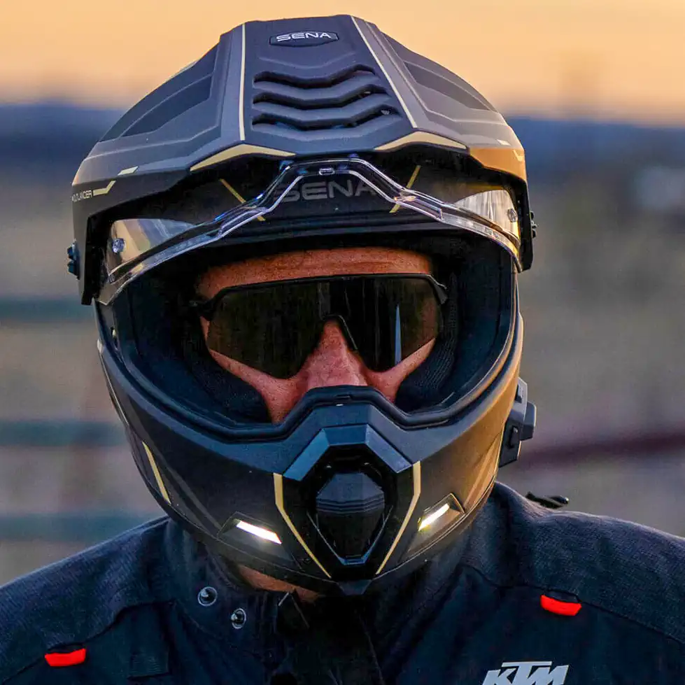 Detalhe do capacete Sena Outlander em acabamento preto fosco, exibindo o sistema de comunicação integrado e as luzes LED traseiras, ideal para motociclistas ADV.