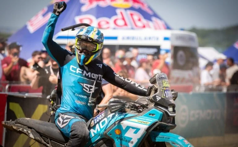 CFMOTO 450MT em ação superando obstáculos extremos em uma trilha de hard enduro na Red Bull Romaniacs, com paisagem montanhosa ao fundo.
