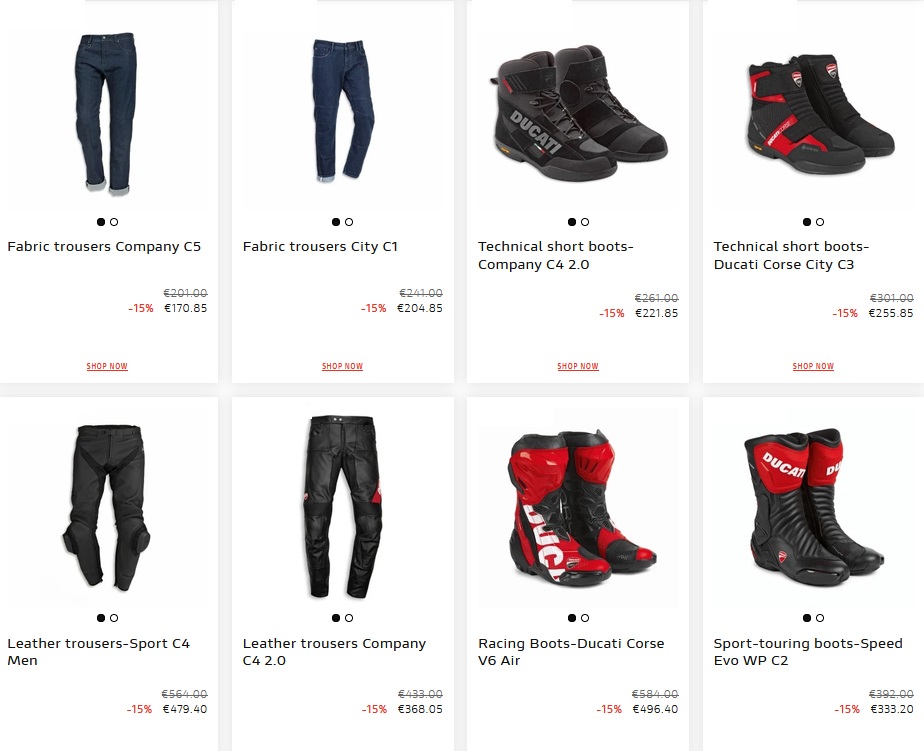 Motociclista vestindo equipamento completo Ducati, incluindo calças e botas, em uma moto esportiva na estrada.