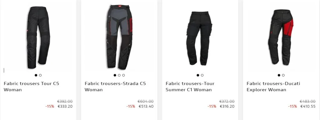 Motociclista vestindo equipamento completo Ducati, incluindo calças e botas, em uma moto esportiva na estrada.