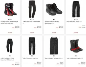 Motociclista vestindo equipamento completo Ducati, incluindo calças e botas, em uma moto esportiva na estrada.