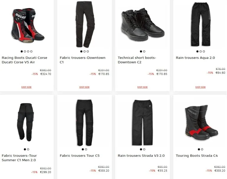 Motociclista vestindo equipamento completo Ducati, incluindo calças e botas, em uma moto esportiva na estrada.