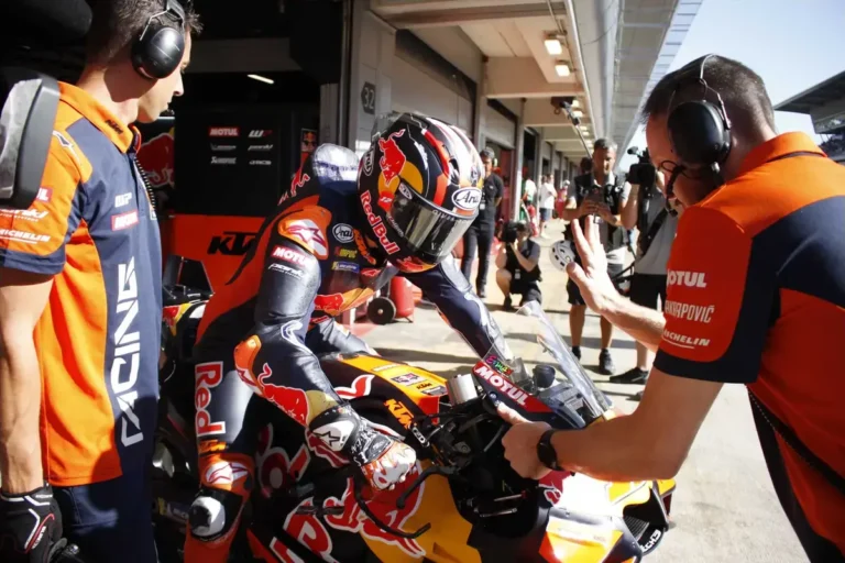 Maverick Viñales pilotando uma moto KTM RC16 em alta velocidade durante uma corrida de MotoGP, destacando sua máquina laranja e preta na pista.