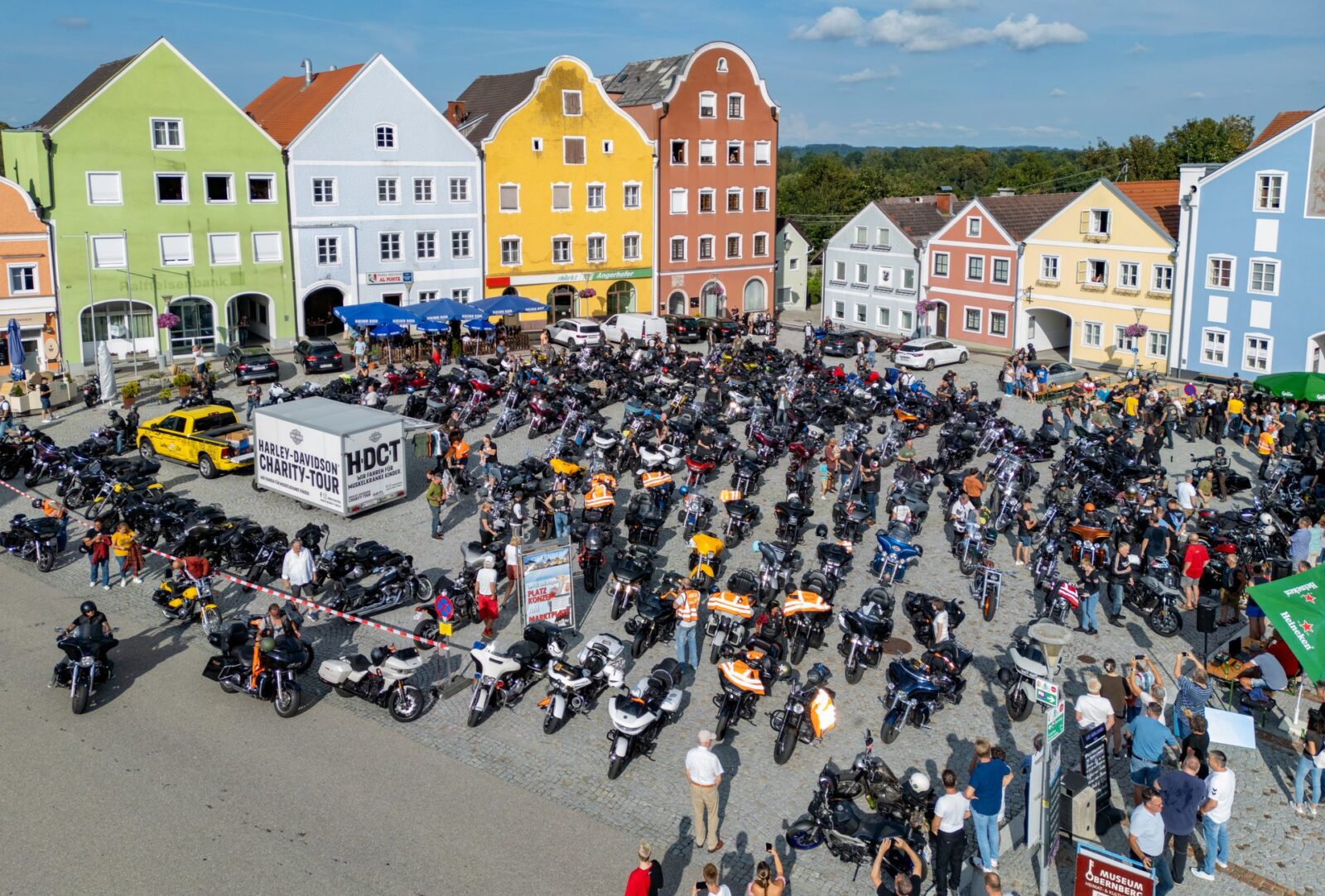 Motociclistas da Harley-Davidson Charity Tour em estrada cênica nos Alpes austríacos, celebrando a solidariedade e 30 anos de evento.