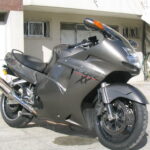 Honda CBR1100XX Super Blackbird em alta velocidade na estrada, destacando seu design aerodinâmico e estilo sport touring dos anos 90.