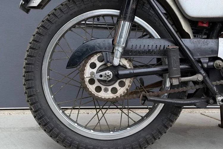Honda CL72 Scrambler de 1964, modelo associado a Elvis Presley, exibida em leilão com detalhes do seu design clássico e motor. Ilustração da moto no contexto de um evento de leilão de veículos antigos.