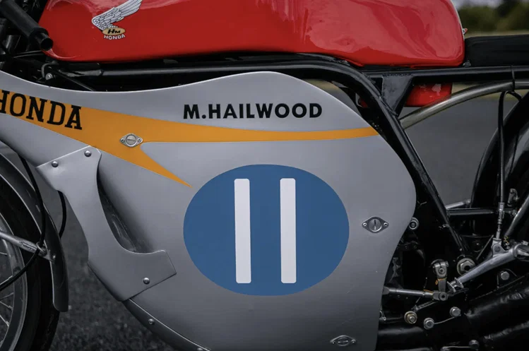 Honda RC173 de corrida pilotada por Mike Hailwood, uma motocicleta clássica de Grand Prix, exibida para leilão, destacando seu design e glória histórica.