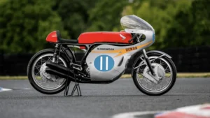 Honda RC173 de corrida pilotada por Mike Hailwood, uma motocicleta clássica de Grand Prix, exibida para leilão, destacando seu design e glória histórica.