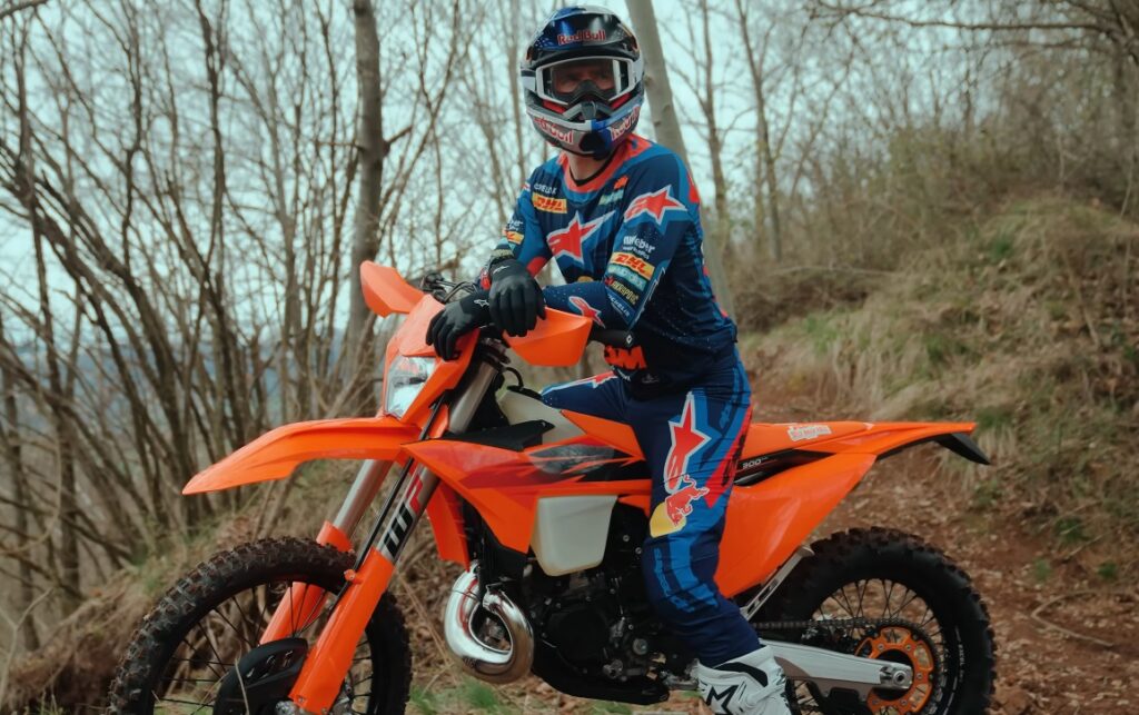 Mani Lettenbichler, piloto de enduro, testando a nova KTM 300 EXC 2027 em trilhas rochosas e desafiadoras, demonstrando a agilidade e potência do modelo.