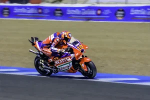 Luca Marini em sua moto Honda RC213V em alta velocidade durante uma corrida de MotoGP, com foco na sua performance.