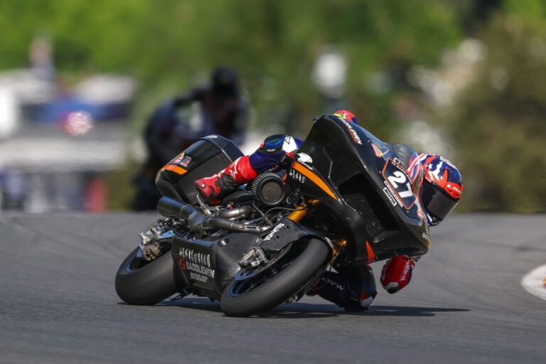 Max Toth pilotando uma motocicleta Harley-Davidson Bagger em alta velocidade durante uma corrida, com a pista de Silverstone ao fundo, ilustrando a competição do Bagger World Cup.