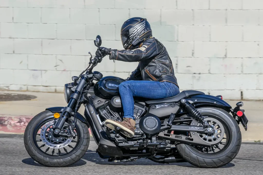 Vista lateral da nova Benda Chinchilla 300, uma motocicleta cruiser compacta com design moderno e elegante, estacionada em um ambiente urbano.