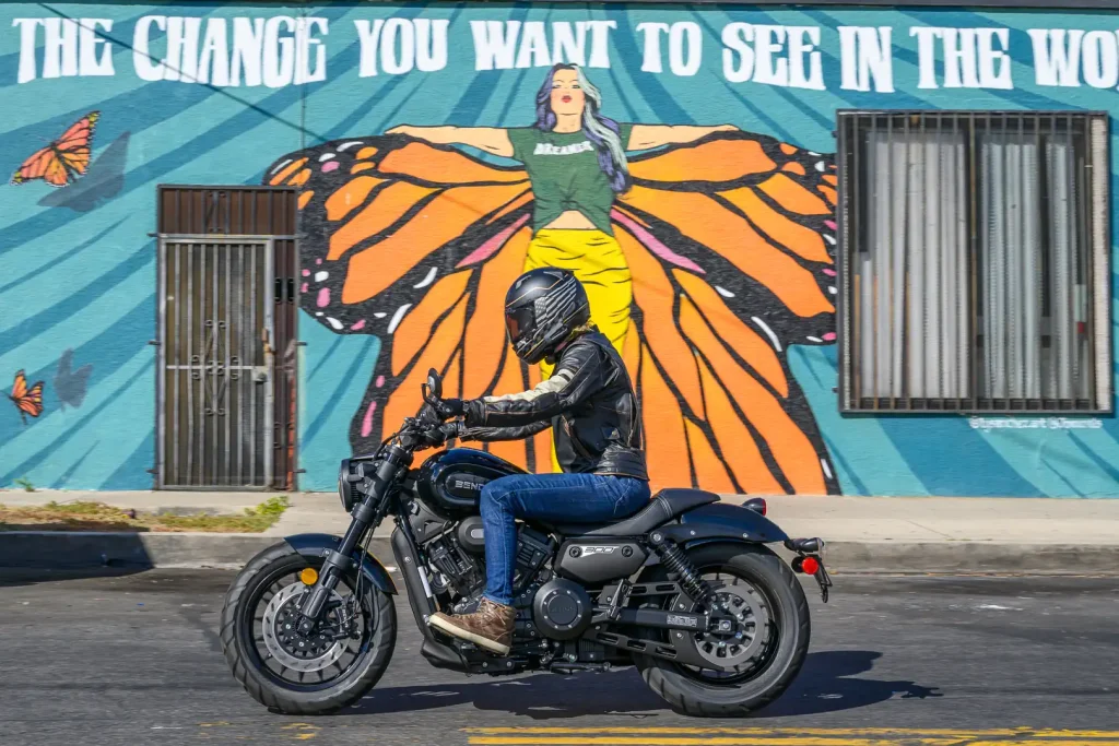Vista lateral da nova Benda Chinchilla 300, uma motocicleta cruiser compacta com design moderno e elegante, estacionada em um ambiente urbano.