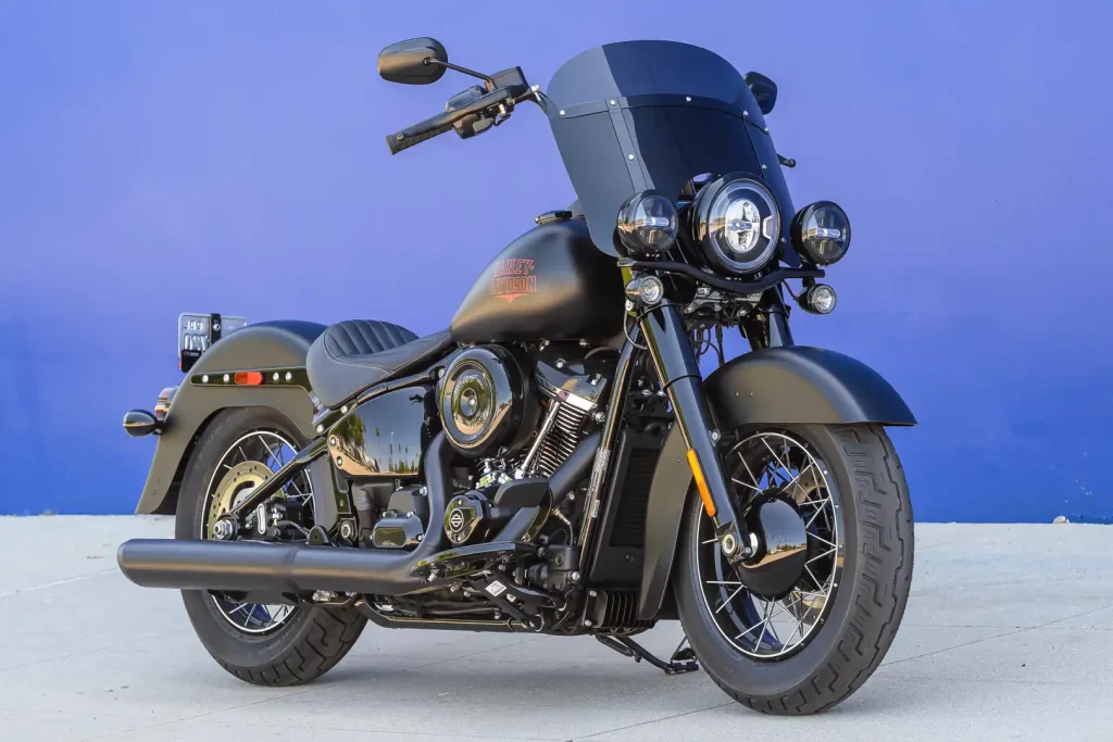 Harley-Davidson Deadwood 2026, uma cruiser Softail na cor Denim Black, exibindo seu assento solo, para-brisa recortado e rodas escuras.