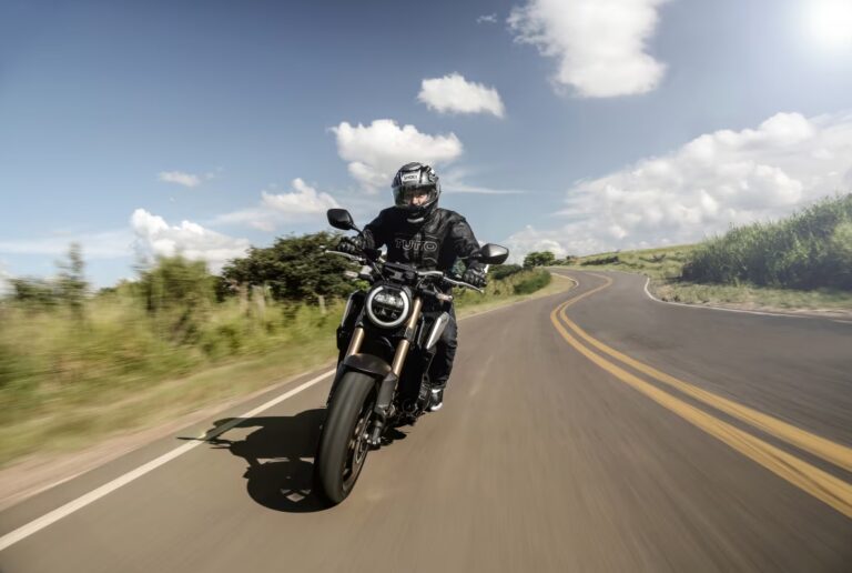 Motociclista pilotando em estrada sinuosa, demonstrando a necessidade de pilotagem defensiva e adaptação às regras do Código da Estrada para garantir segurança.