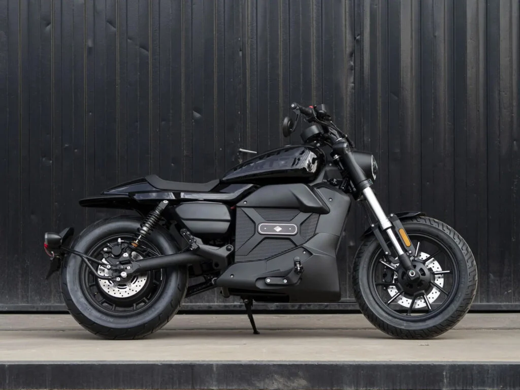Velca Vortex Black Edition, uma motocicleta elétrica com design moderno e elegante em acabamento preto fosco, estacionada em um ambiente urbano.