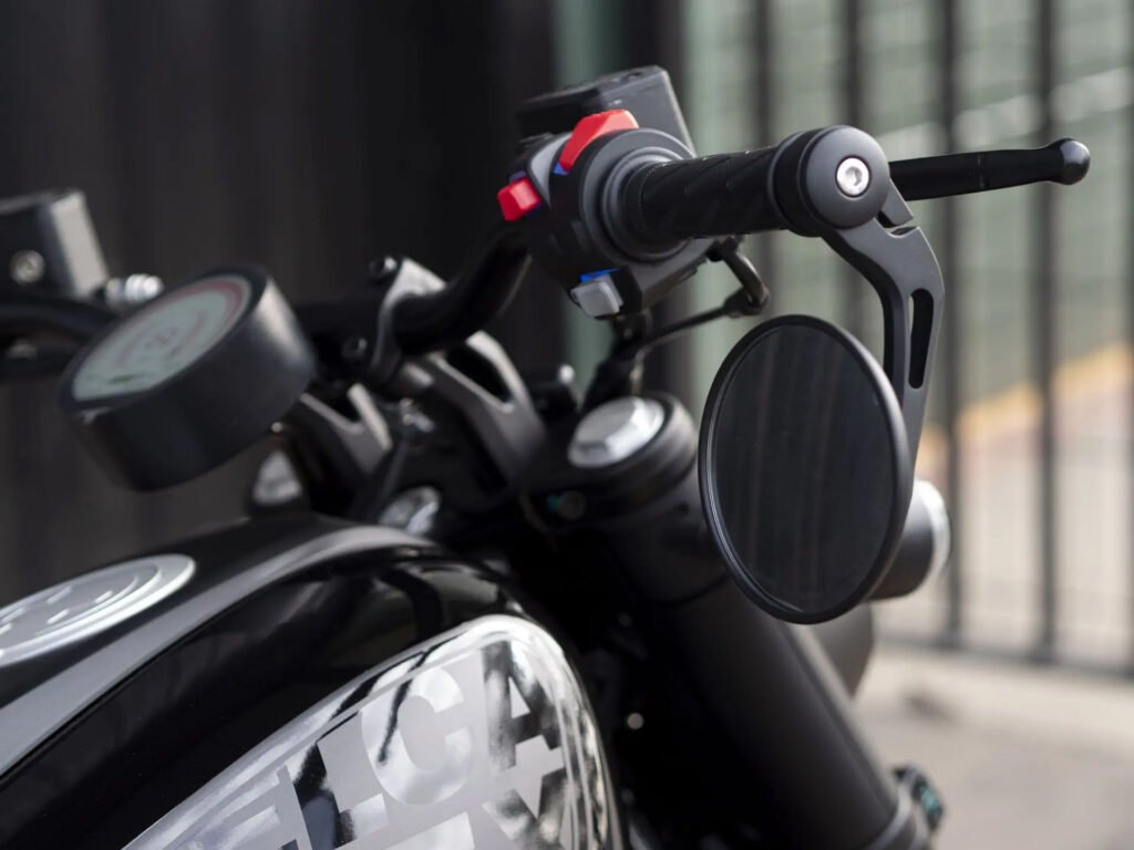 Velca Vortex Black Edition, uma motocicleta elétrica com design moderno e elegante em acabamento preto fosco, estacionada em um ambiente urbano.