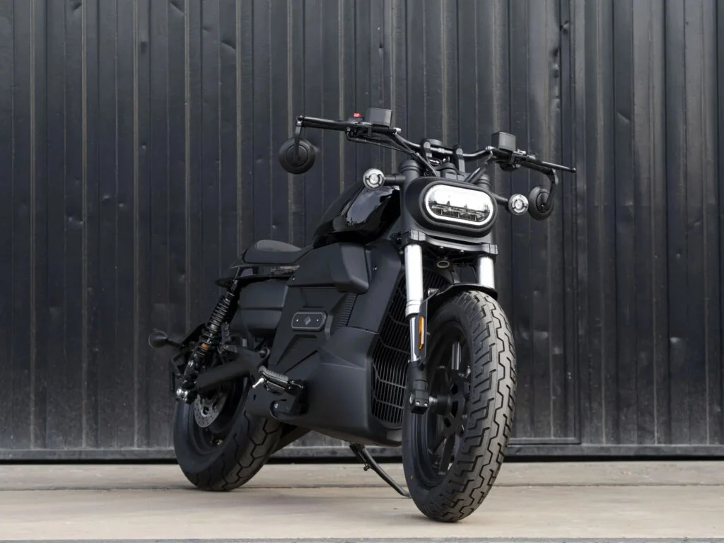 Velca Vortex Black Edition, uma motocicleta elétrica com design moderno e elegante em acabamento preto fosco, estacionada em um ambiente urbano.