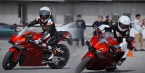 A ZXMOTO 820RR esportiva, uma motocicleta chinesa tricilíndrica de 135 cv, em ação na pista de corrida com Richard Hammond e a piloto Zhang Xue, destacando seu design agressivo e performance competitiva no Mundial de Supersport.