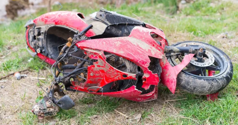 Mecânico inspecionando o chassi de uma moto usada em busca de sinais de solda ou recuperação após acidente, com ferramentas e ambiente de oficina ao fundo.