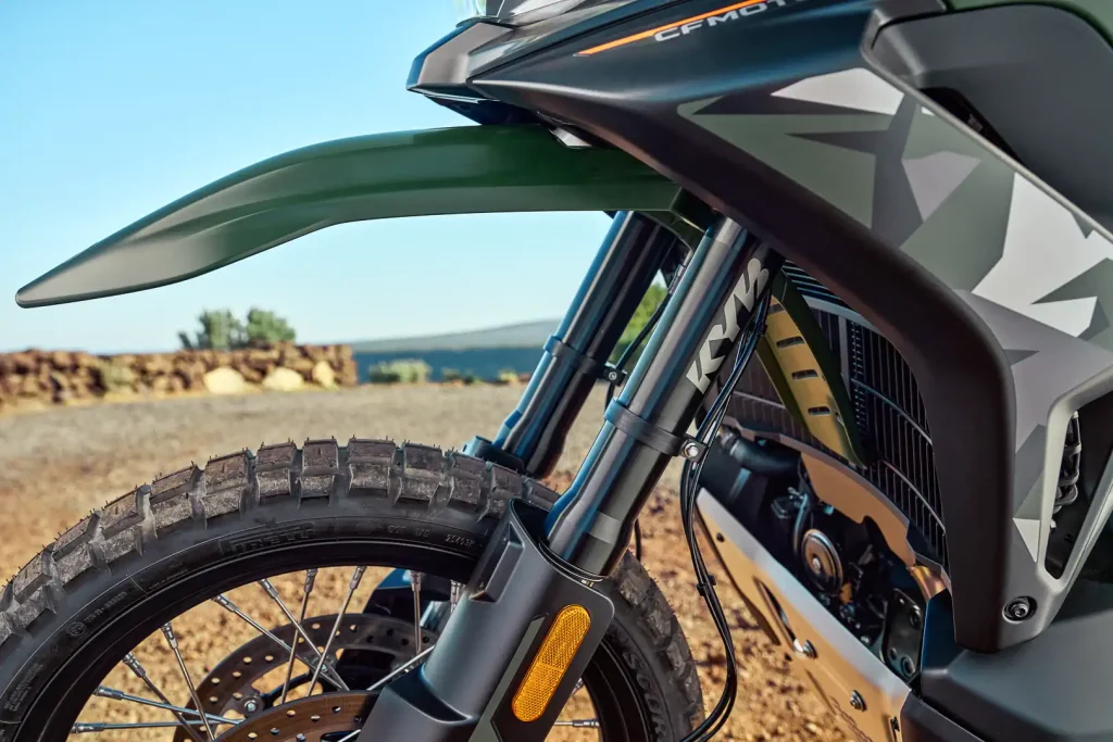 Detalhe da frente da CFMoto Ibex 950 Adventure Bike, mostrando seu design agressivo, faróis de LED e suspensão dianteira de longo curso.