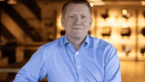 Paul Stroud, Chief Commercial Officer da Triumph Motorcycles, sorrindo em um evento da marca, representando seu legado de crescimento.