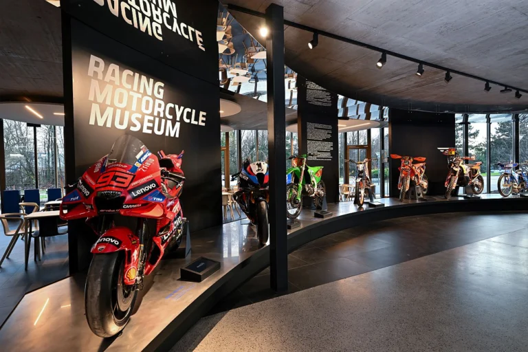 Exposição da Marelli no FIM Racing Motorcycle Museum mostrando a evolução das unidades de controle eletrônico (ECUs) em motocicletas de competição.