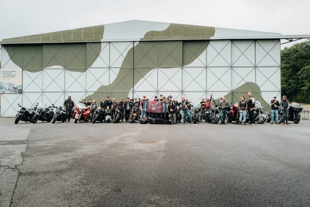 Motocicletas Indian de diversas épocas reunidas em frente ao histórico Brooklands Museum, celebrando os 125 anos da marca, com a pista de corrida ao fundo.