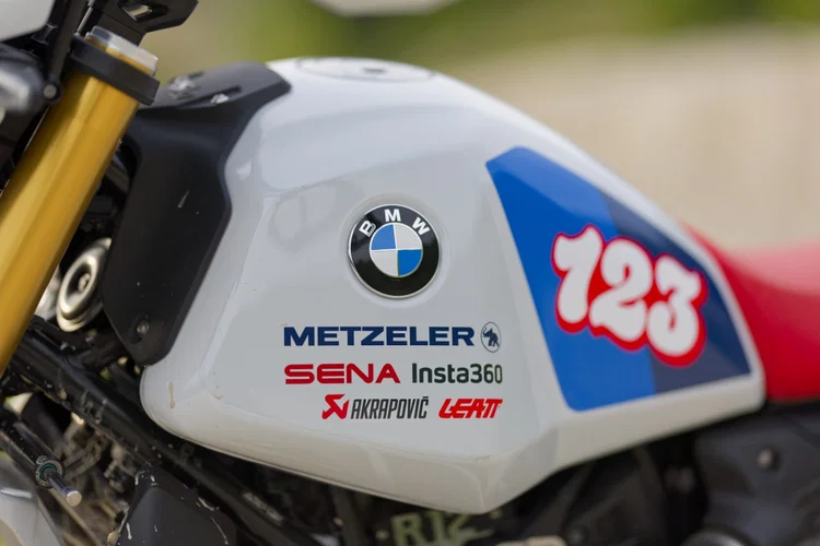 Imagem ilustrativa de um motociclista usando um capacete BMW GS Rallye Carbon com sistema de intercomunicador Sena integrado, em um cenário de aventura off-road.