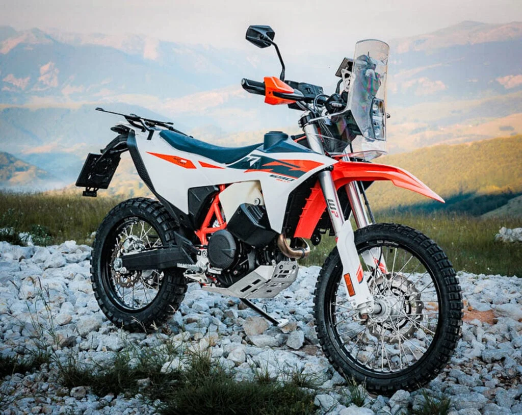KTM 690 Rally 2027 em destaque, exibindo seu design robusto e pronto para rali, com carenagem de competição e tanque de combustível de grande capacidade.