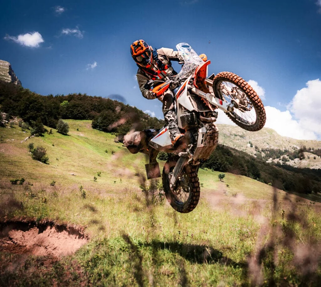 KTM 690 Rally 2027 em destaque, exibindo seu design robusto e pronto para rali, com carenagem de competição e tanque de combustível de grande capacidade.