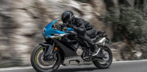 Duas motocicletas de média cilindrada, uma com motor de dois cilindros e outra com motor de quatro cilindros, lado a lado em uma estrada sinuosa, simbolizando a competição de mercado.
