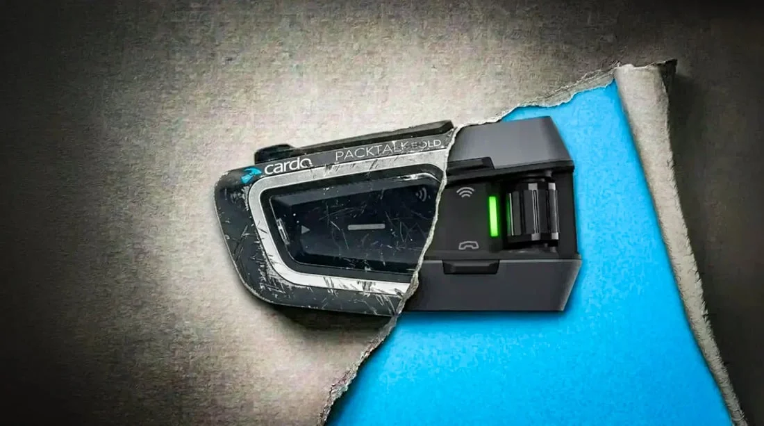Imagem detalhada de um comunicador Cardo PACKTALK Edge montado em um capacete de motociclismo, destacando seu design moderno e botões de controle.