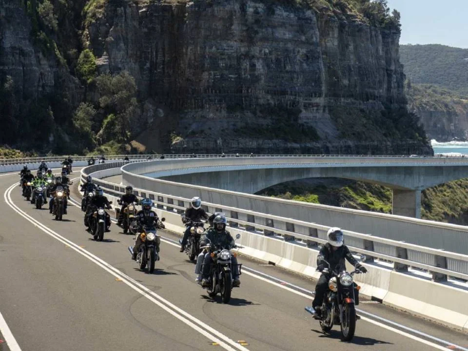 Motociclistas Royal Enfield se preparando para a largada do One Ride 2026 em uma rua ensolarada, com diversas motos alinhadas.