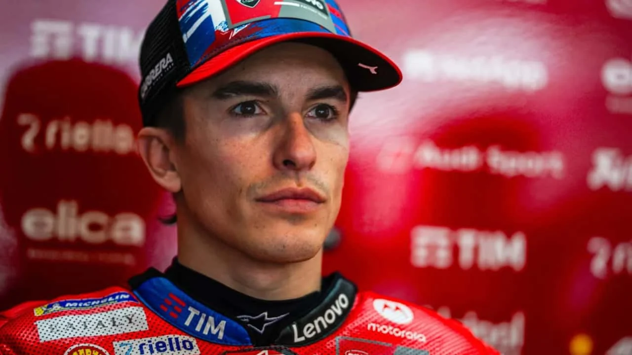 Marc Marquez em sua moto de MotoGP, exibindo postura agressiva em uma curva, com foco em seu braço direito e a força necessária para a pilotagem em alta performance.