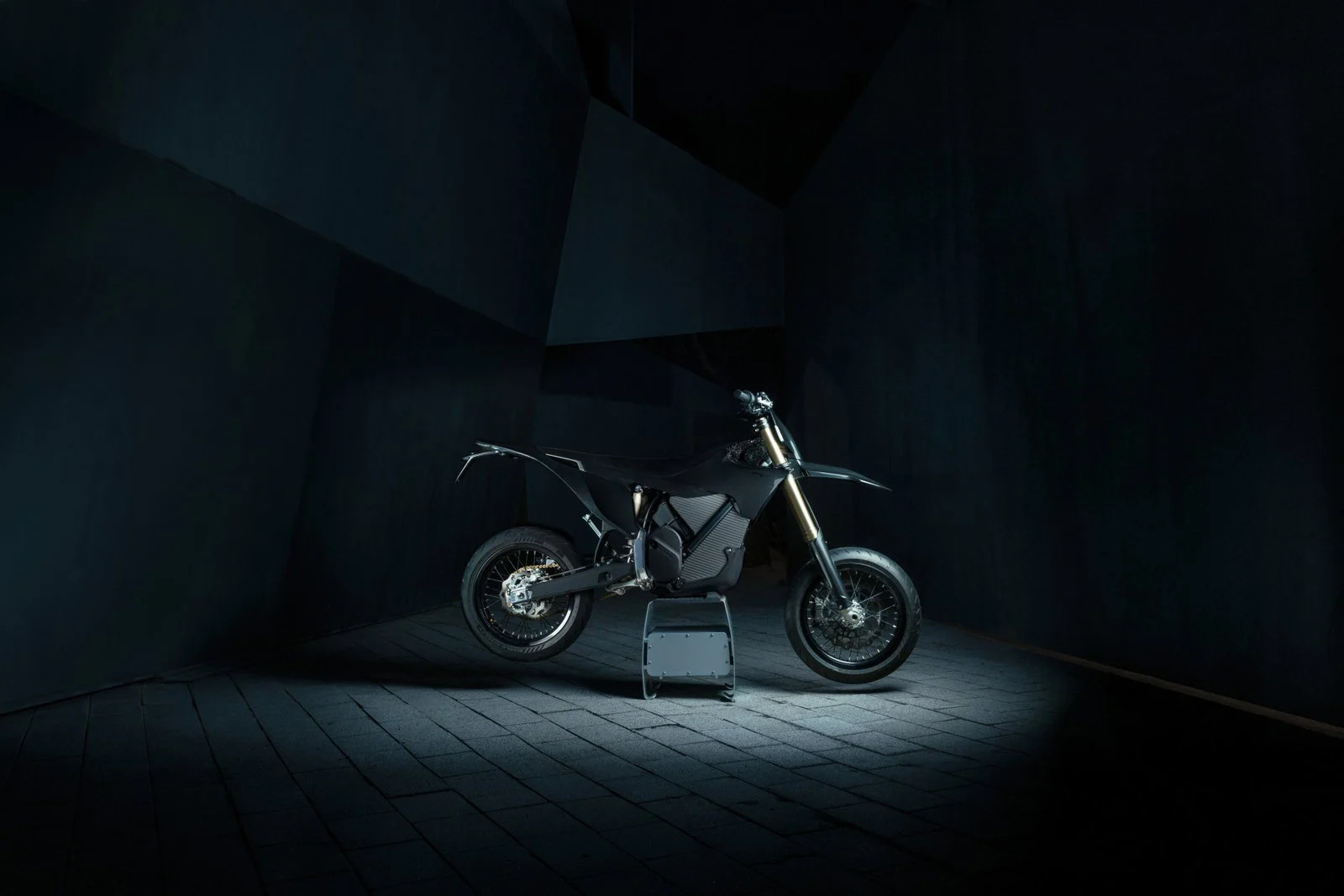 Stark Varg SM Sköll supermoto elétrica de alto desempenho, vista lateralmente em acabamento totalmente preto com detalhes dourados.