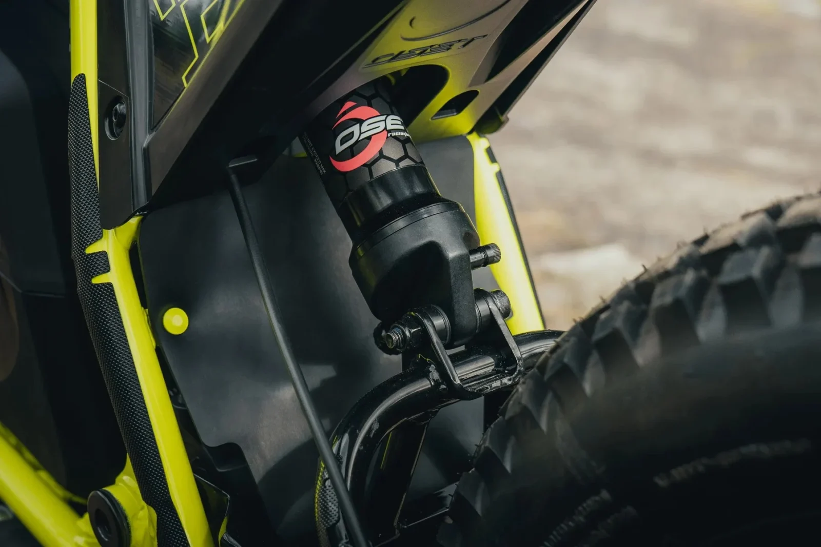 Triumph TXP 20 em ação, em um cenário de trilha com obstáculos naturais, exibindo sua agilidade e design específico para trials.