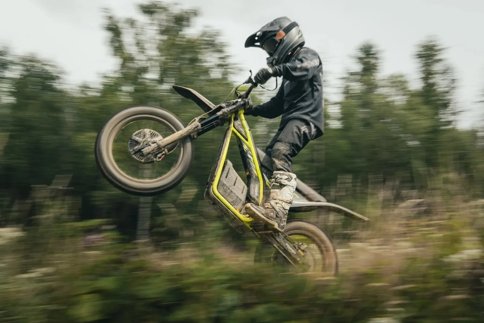Triumph TXP 20 em ação, em um cenário de trilha com obstáculos naturais, exibindo sua agilidade e design específico para trials.